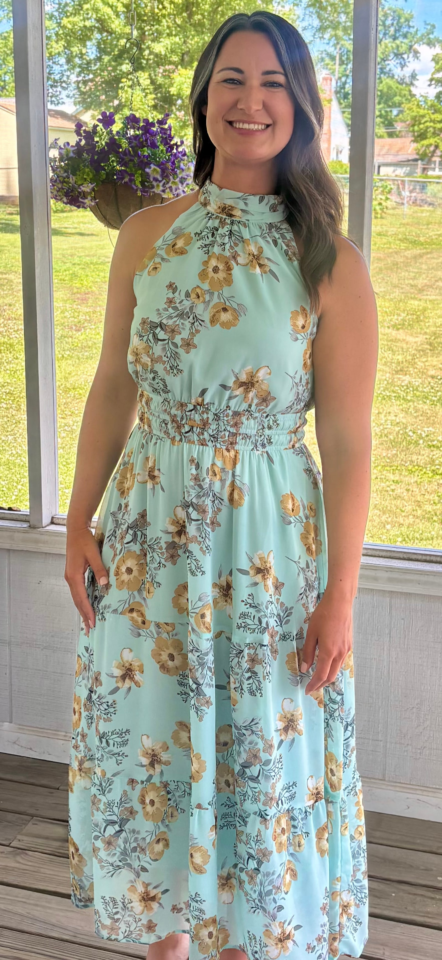 Rebecca Norelli standing on a porch in an aqua floral dress